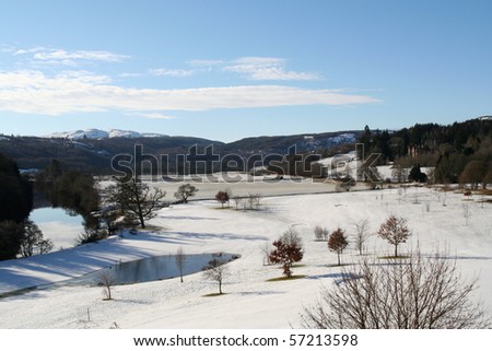 A golf course in a quiet valley in Scotland is covered in thick snow on a bright winters day.