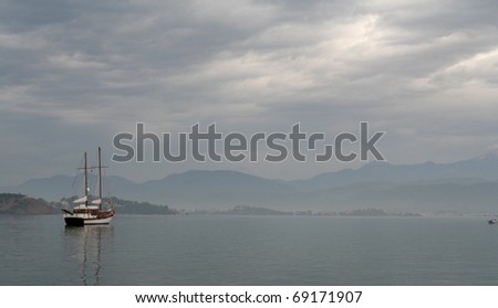 Lone boat in Fethiye harbor, Turkey, grey skies hint of light and calm water.
