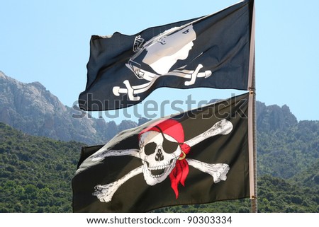 Two flags seen on Corsica, France. Corsican flag with crossed swords and the Skull and crossbones.
