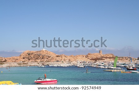 L\'lle Rousse, Corsica. Leisure boats in a safe harbor and lighthouse on the eponymous red rocks.