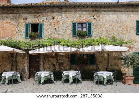 Tables and awnings outside an attractive Tuscan country restaurant.
