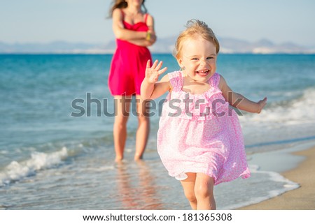 Little girl in pink dress running on the beach