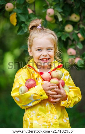 Little girl holding apples in the garden
