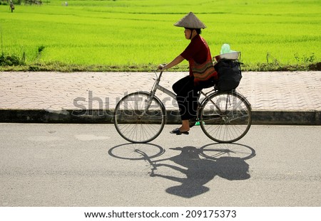 Dien Bien Phu, Dien Bien, VIETNAM, July 28, 2014: A Thai woman Black people cycling are accompanied by the bamboo baskets on their way to market.