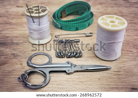 Vintage Background with sewing tools/Sewing kit. Scissors, bobbins with thread and needles on the old wooden background
