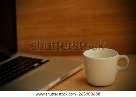 Hot latte coffee cup and laptop on wood background and texture.