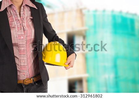 Engineer holding yellow helmet for workers security on background