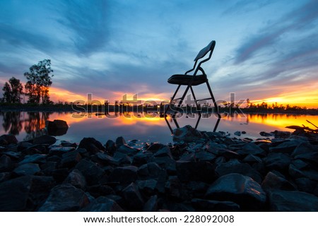 alone chair on the water in sunset