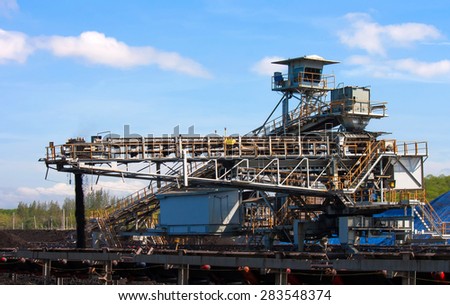 Large conveyor belt carrying coal and emptying onto a huge pile.