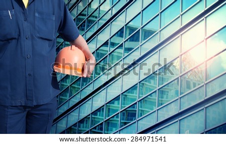 engineer holding orange helmet for workers security on office buildings in blue color tone