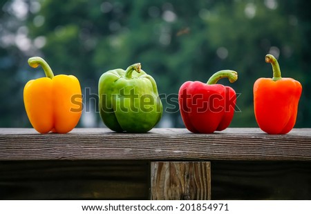 Four different colored peppers on a wood ledge