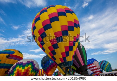 Hot air balloons getting ready for lift off against blue sky and clouds