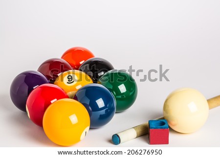 Nine Ball racked in a diamond shape on a plain white background left side with cue stick, chalk and cue ball ion foreground.
