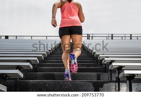Young fit female athlete running up bleachers at a stadium to illustrate \