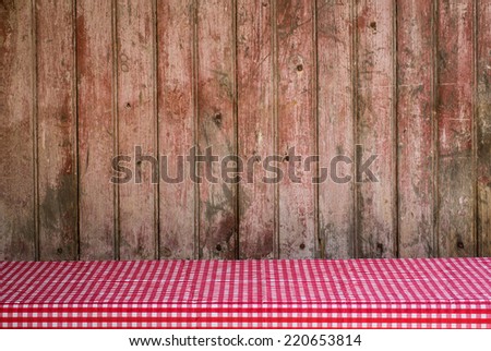 Old Barn door with faded paint for use as a background with red and white checkered tablecloth in foreground.
