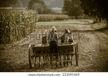 Young amish farmer sowing a field during the fall season with a retro filter applied.