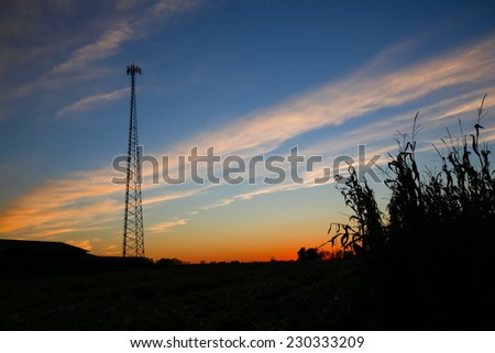Silhouette of cellular tower at dusk with colorful sky.