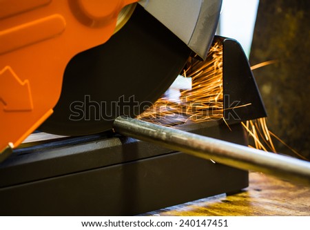 Cut off saw wheel is cutting through a steel pipe as sparks fly.