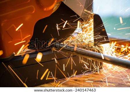 Cut off saw wheel is cutting through a steel pipe as sparks fly.