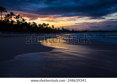 Beautiful sunset view of surf at beach with golden glow of sun reflecting off of water.