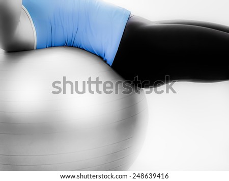 Partial side view of woman on silver exercise ball with soft glow filter applied.