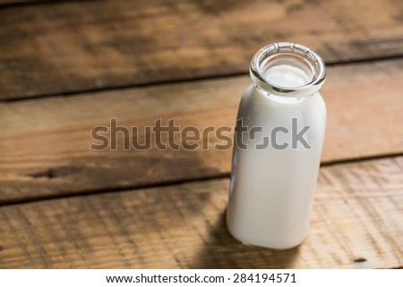 Old style bottle of milk sitting on wood table shot from slightly above with selective focus.