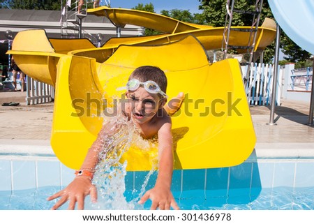 happy child playing with the slide in the pool