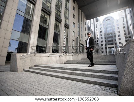 Handsome businessman standing on stairs of business center