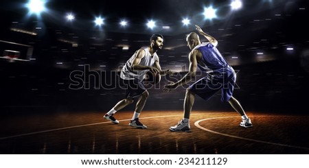 Two basketball players in action in gym in lights panorama view