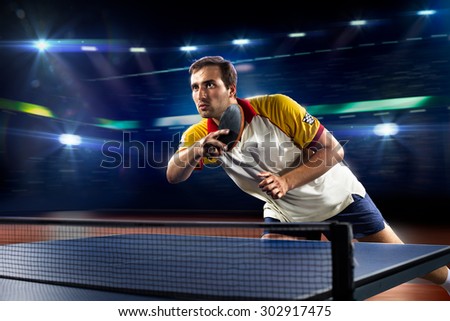 young sports man tennis player is playing on black background with lights