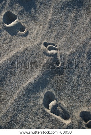Footprints...bare feet and shoe prints in sand.