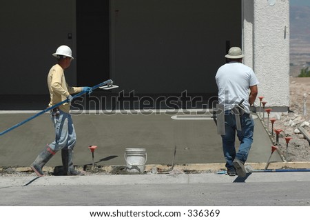 Two laborers finishing the grade on concrete driveway