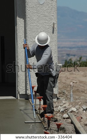 Workman finishing concrete driveway at new home