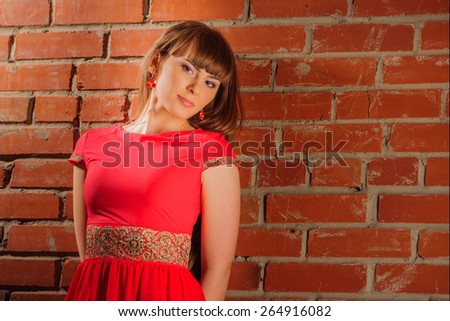 Young girl posing in studio in national dress, beside brick wall