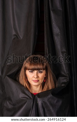 Young girl posing in studio behind black curtains