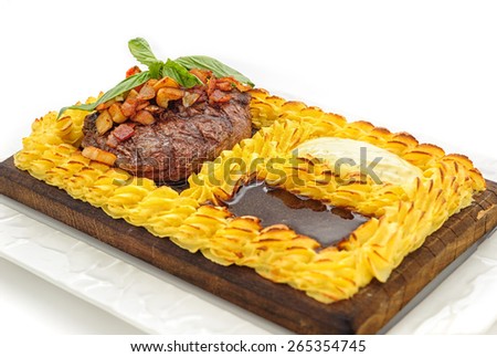 Meat steak surrounded with cake of mashed potatoes, studio shot