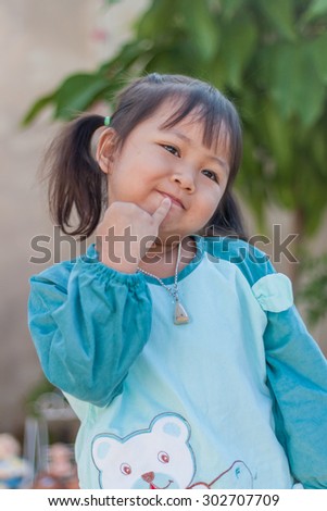 portrait of cute little asian girl posing pointing lip gesture