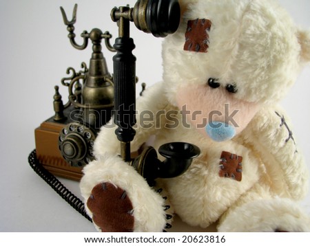 The toy bear cub calls by phone or waits for a call. Old phone.