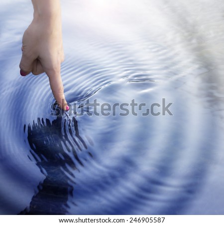 Girl touching the water with  with ripple effect.