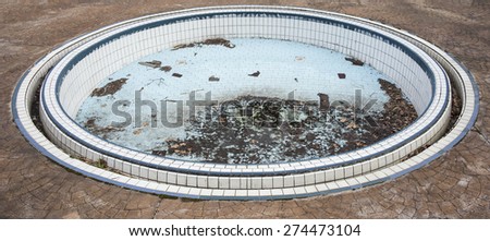 Circular shape, abandoned swimming pool full of dirt.