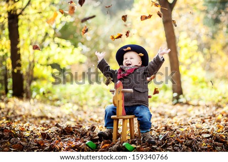 Little Boy On The Wooden Rocking Horse In The Autumn Forest