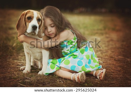 little girl is hugging  dog outdoors
