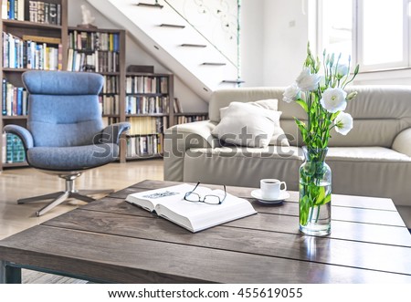 Living room wooden table with white roses, coffee cup and book