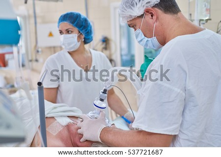 anesthesiologist medical doctor hold anesthesia breathing mask, woman patient lying in operating surgery room, hospital equipment and the doctor put a mask