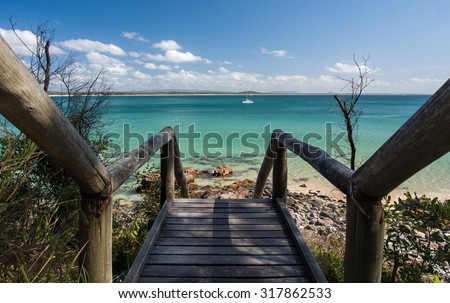 Wooden Stairs Leading to a Pristine Beach Paradise Overlooking a White Sail Boat and Mountains During a Beautiful Summer Day, Noosa National Park, Noosa Heads, Sunshine Coast, Queensland, Australia