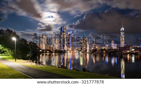 Full Moon Night View of The Iconic Gold Coast City Tourism Skyline Reflecting In The Canal From A Park With Street Lights And Dramatic Clouds, Surfers Paradise, Queensland, Australia