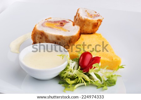 Rolls of tender chicken fillet with bacon and cheddar cheese. Served on a large platter with polenta, arugula, cherry tomatoes and a white cream sauce.