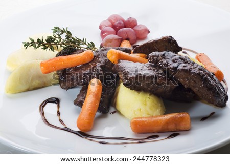 Sauteed sliced beef liver garnished with apples and baby carrots, accompanied with pickled onions. Soy sauce drops on plate and sprig of thyme make the food savory and delicious.