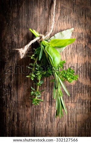 Fresh herbs hanging isolated on a wooden background, thyme, basil, rosemary, parsley