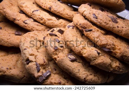 Chocolate chip cookies stacked up on a plate, ready to be served.